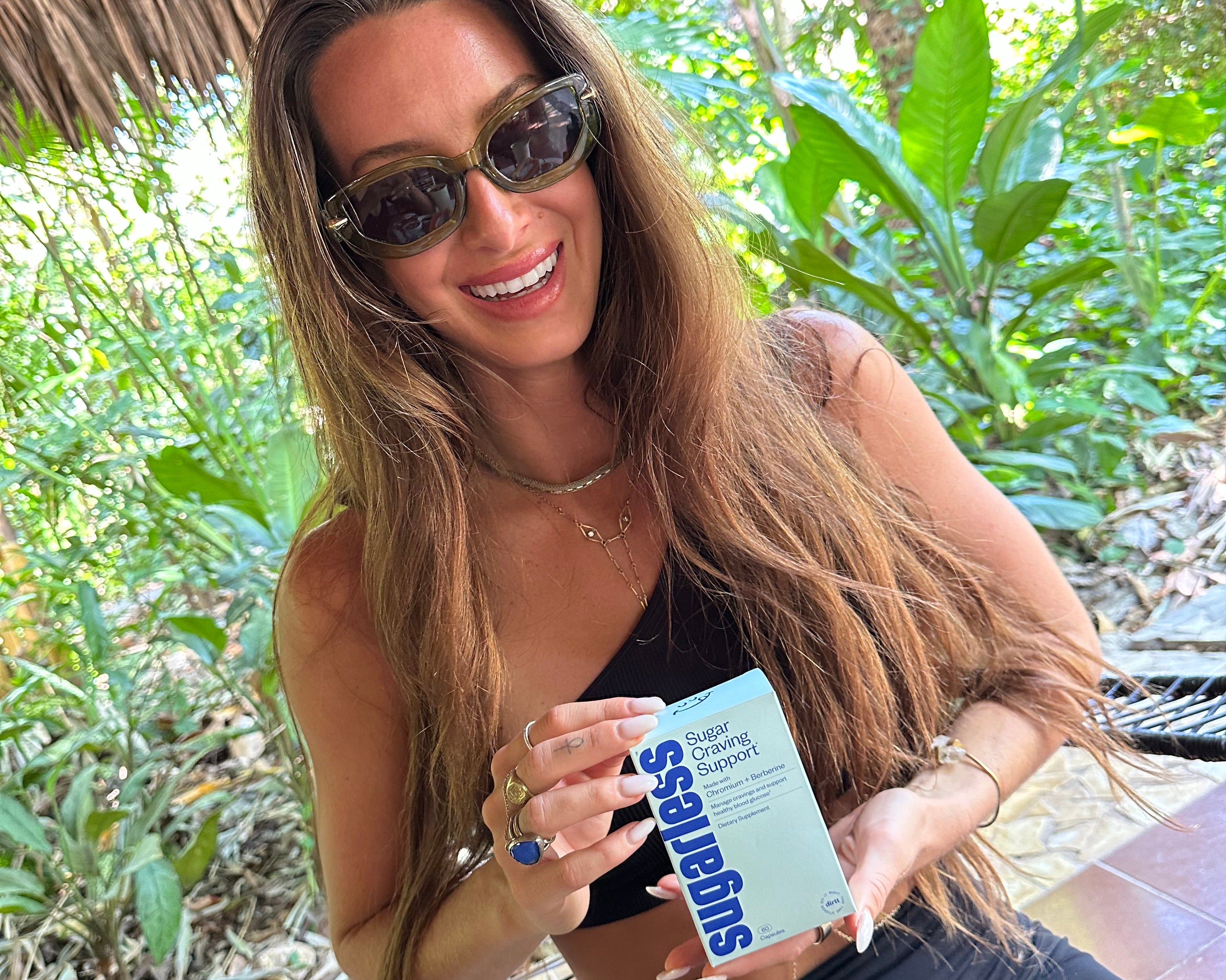 a woman holding a box Sugarless Sugar Craving Support supplement in an outdoor setting